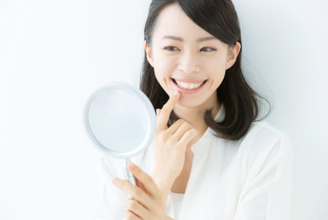 鏡で歯をチェックする女性